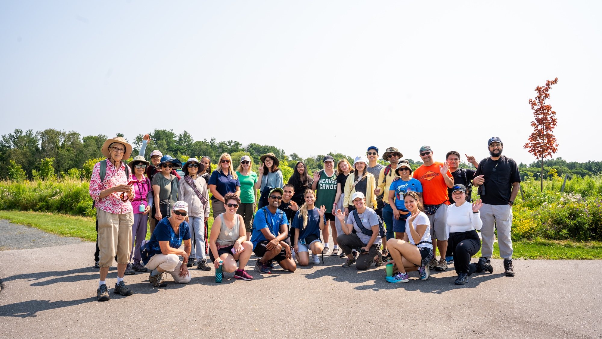 A big, smiling group on a trail on a sunny summer day